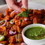 dipping a piece of tofu Koliwada into the mint chutney