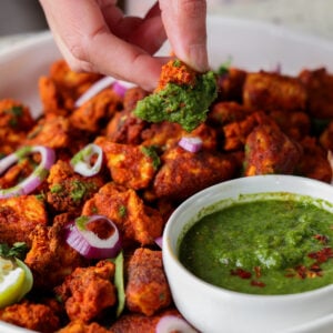 dipping a piece of tofu Koliwada into the mint chutney