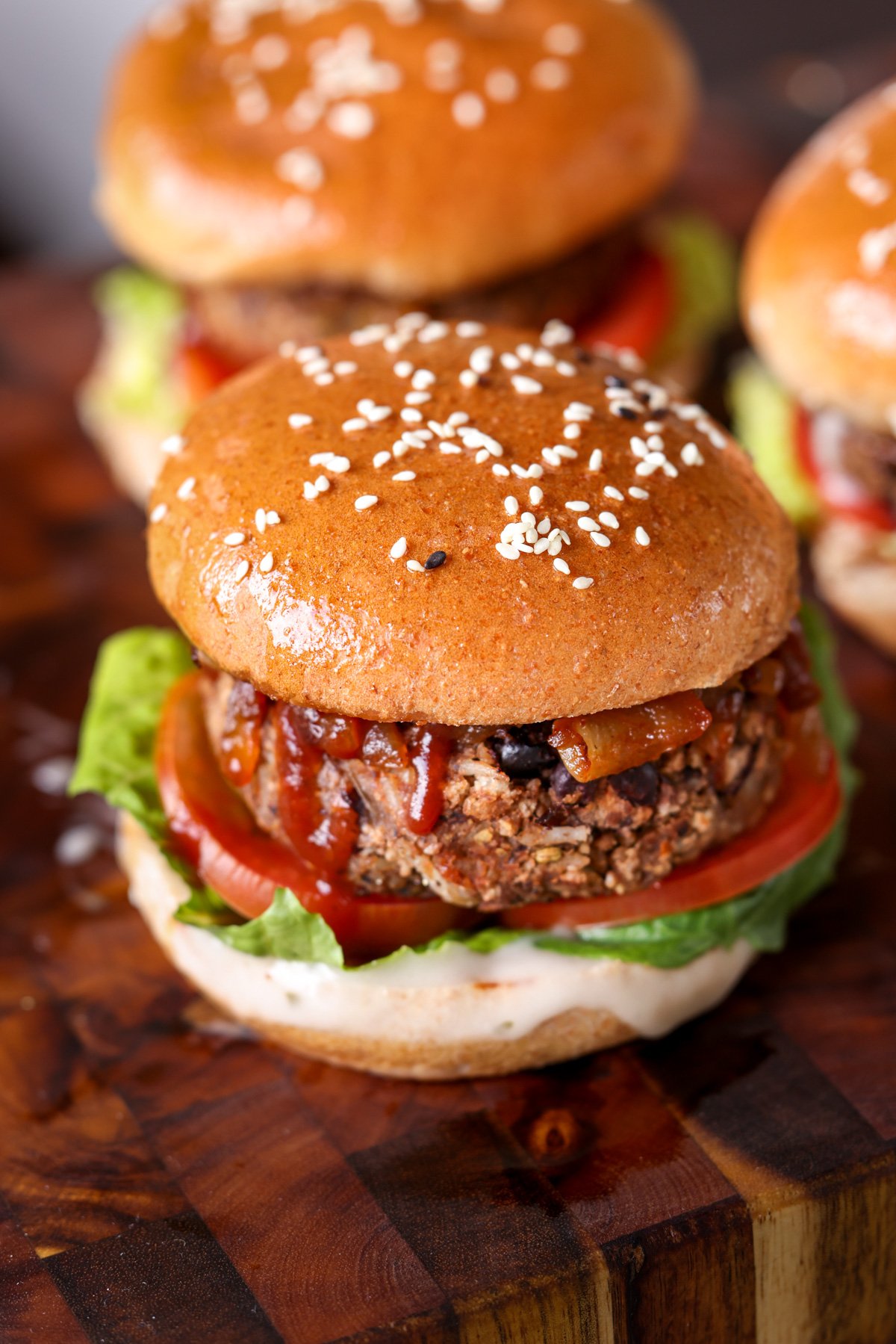 The veggie burgers on sesame buns on a wooden cutting board.