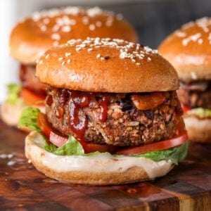 Three black bean burgers on a wooden cutting board.