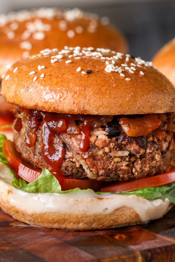 Three black bean burgers on a wooden cutting board.
