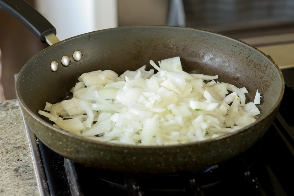 Sliced onions in a black skillet.
