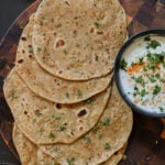Indian flatbread on a cutting board with yogurt dip.