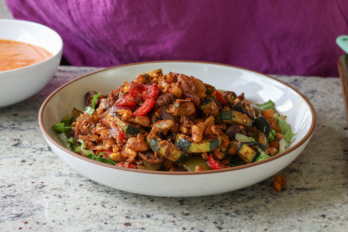 cajun sheet pan beans veggies in the bowl before adding dressing