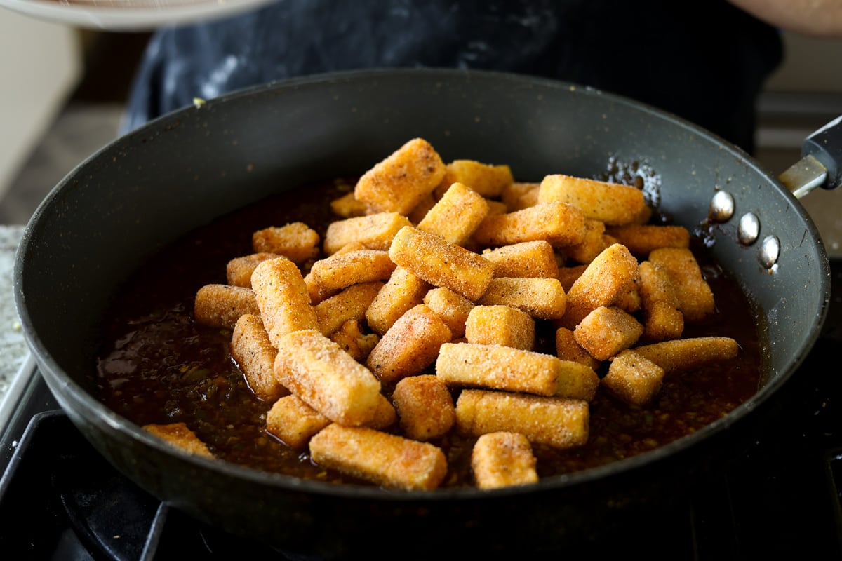 adding crispy tofu to the Manchurian sauce in the pan