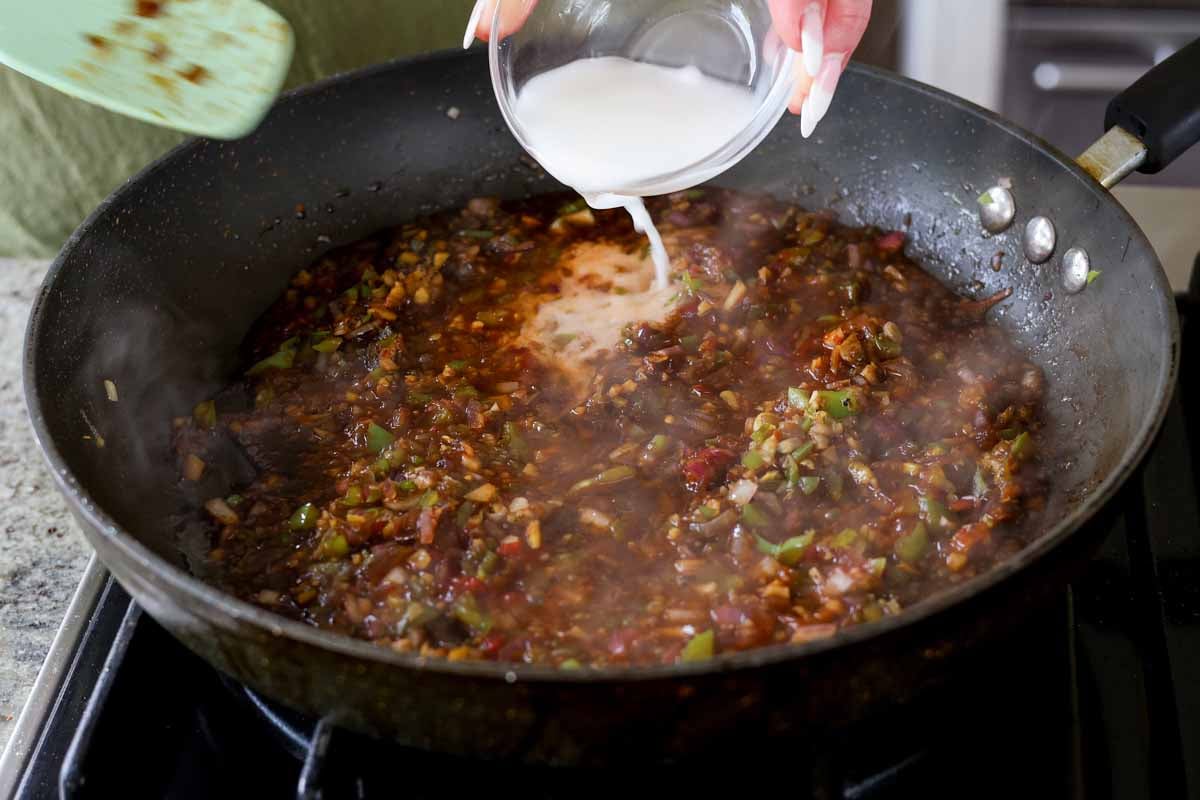 adding cornstarch mixture to the sauce in the pan