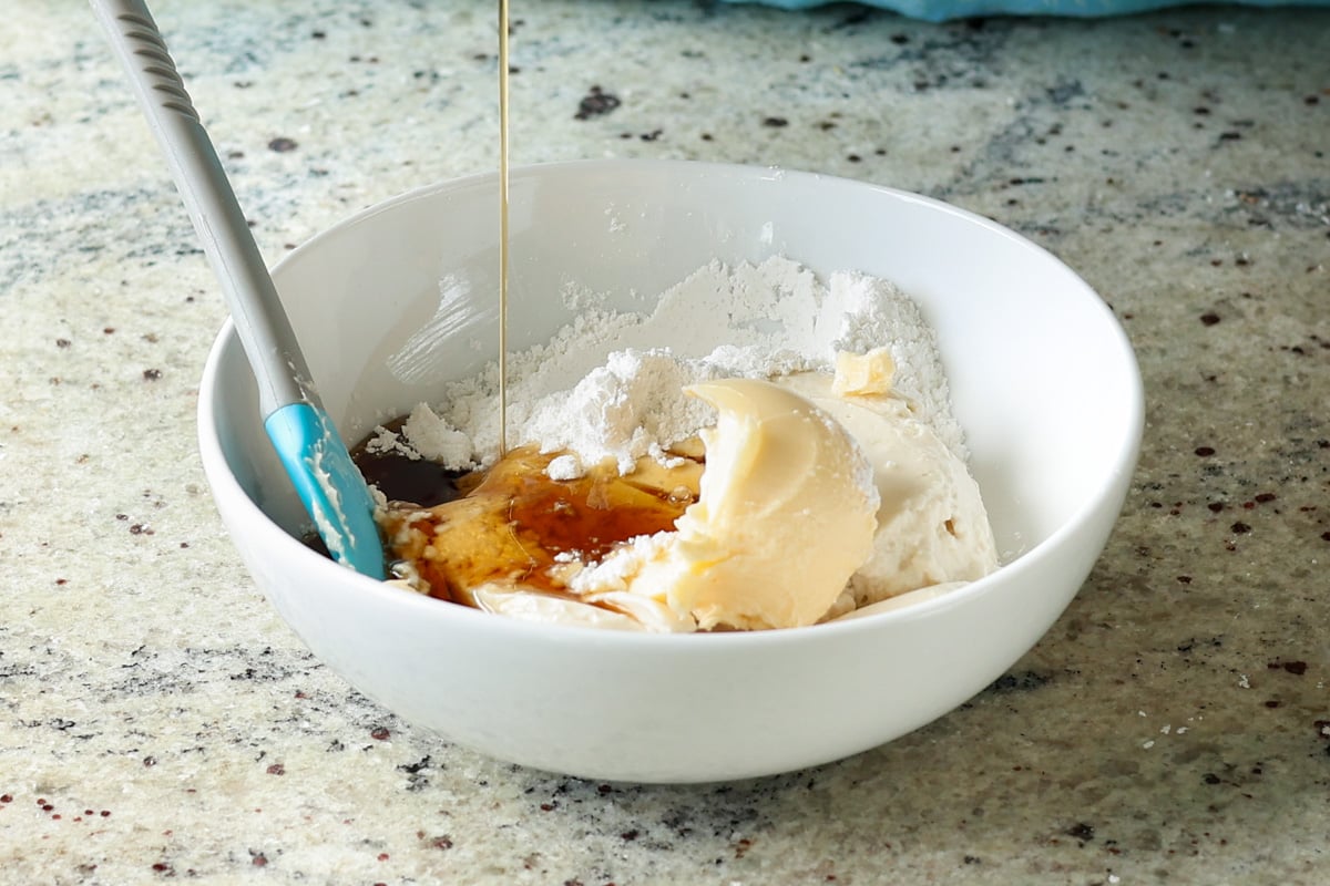 mixing the cream cheese frosting ingredients in a bowl