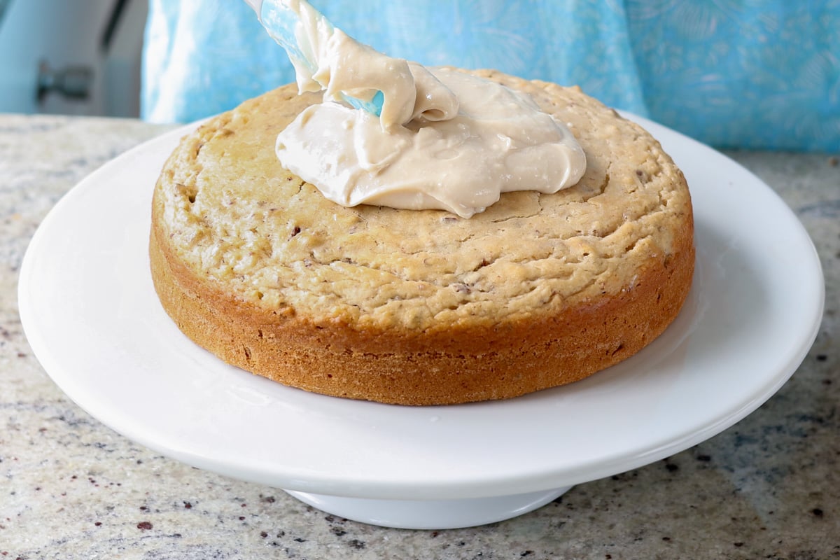 adding cream cheese frosting to the Italian cream cake