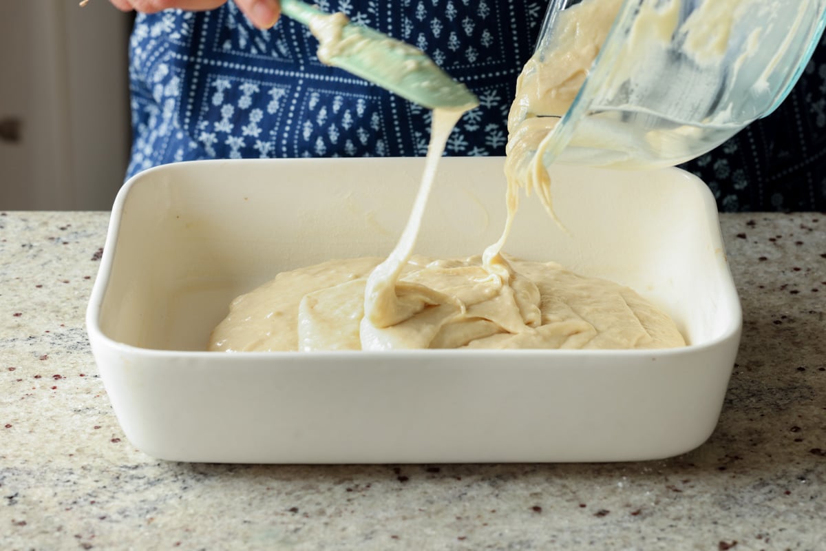 pouring cake batter into the greased pan
