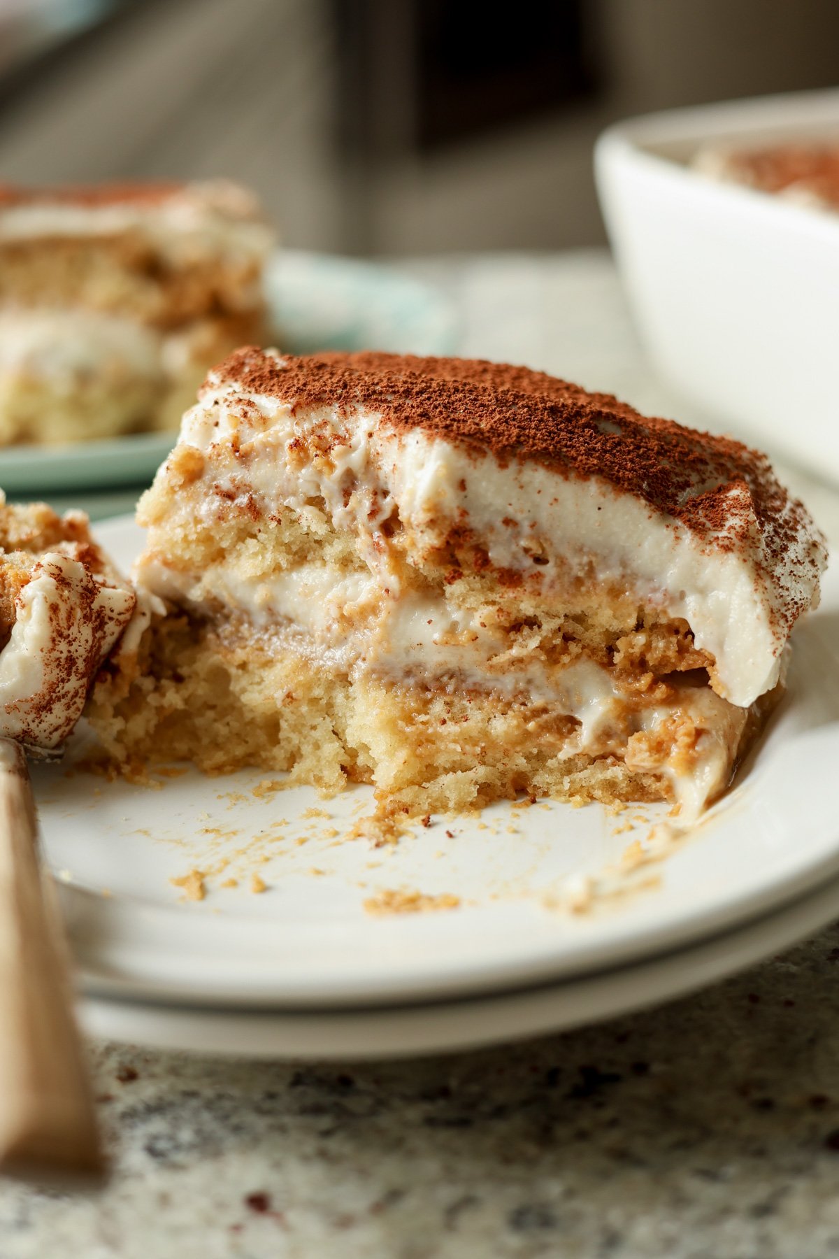 slice of chai tiramisu cake on a plate with a fork taking a bite