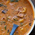 pan of tortellini soup with a ladle in it