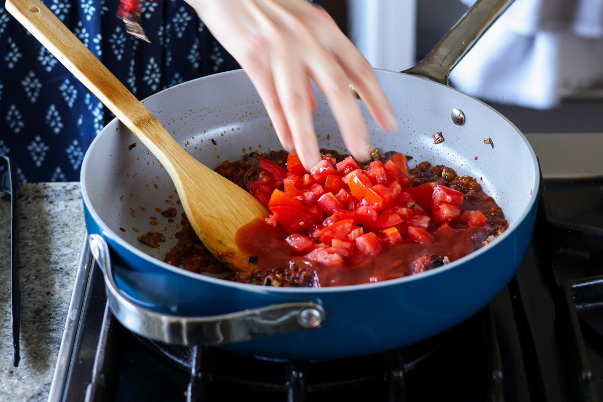 adding tomatoes to the pan