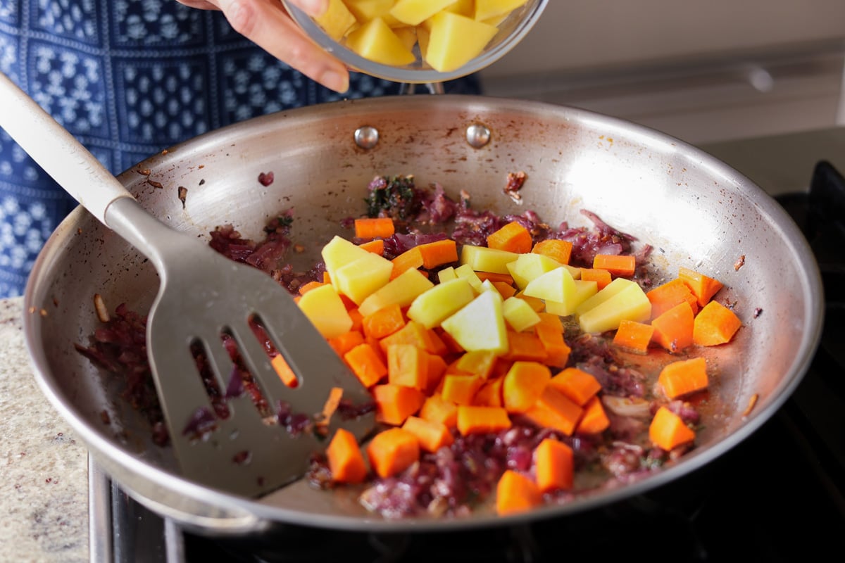 adding carrots and potatoes to the pan