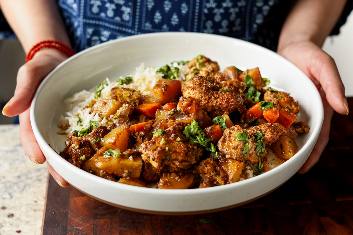 braised tofu and veggies in a bowl with rice and herb sauce