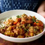 braised tofu and veggies in a bowl with rice and herb sauce