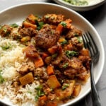 braised tofu and veggies in a bowl with rice and herb sauce