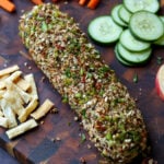 holiday cheese log on a party platter with veggies, chips, pita, and apple slices