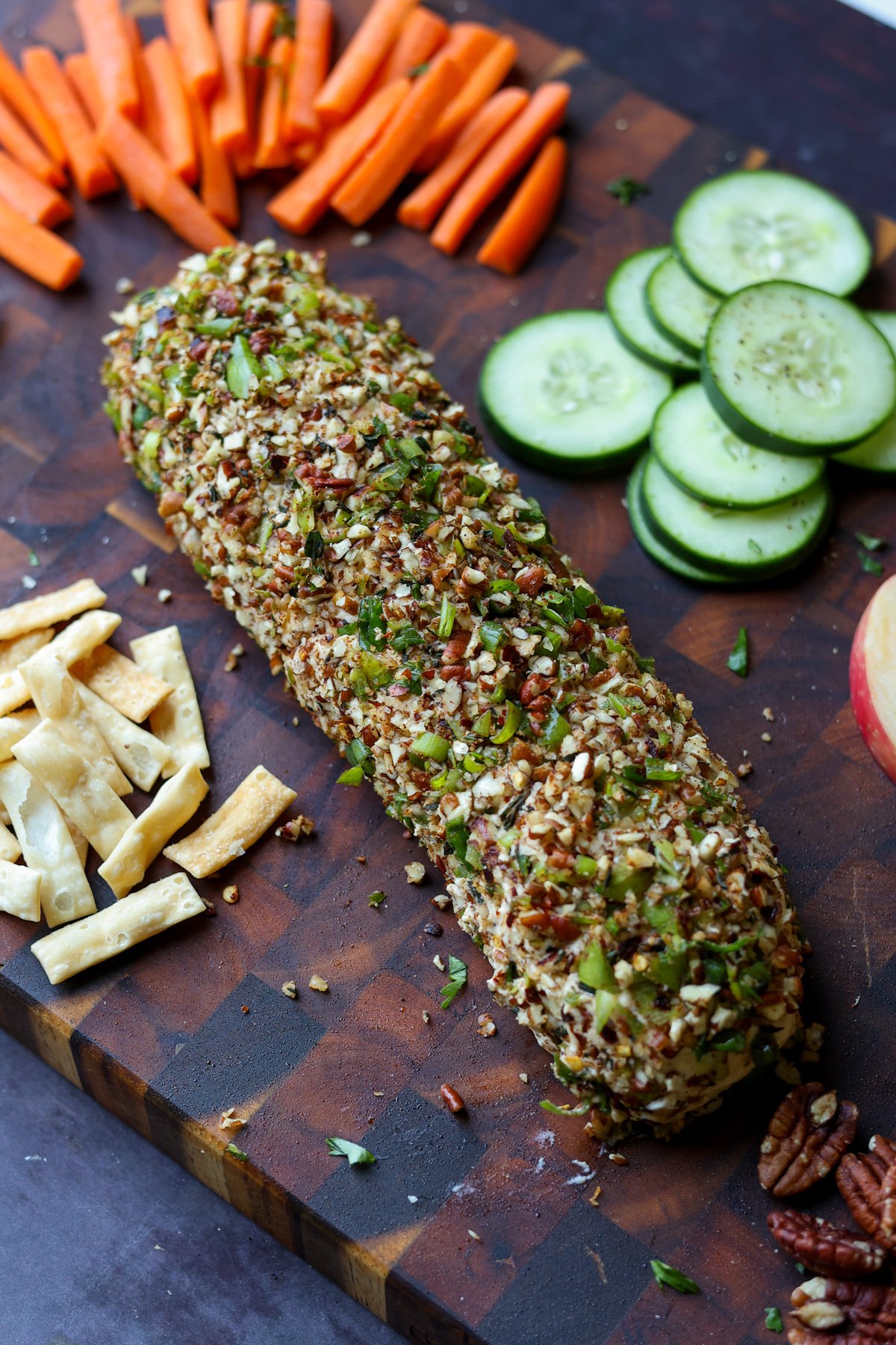 holiday cheese log on a party platter with veggies, chips, pita, and apple slices