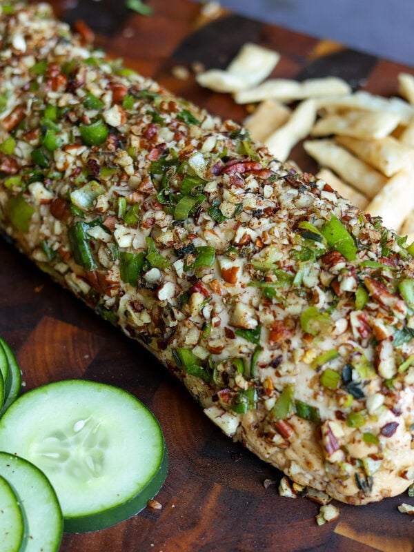 holiday cheese log on a party platter with veggies, chips, pita, and apple slices