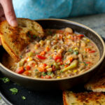 scooping up lemon white bean soup with garlic bread