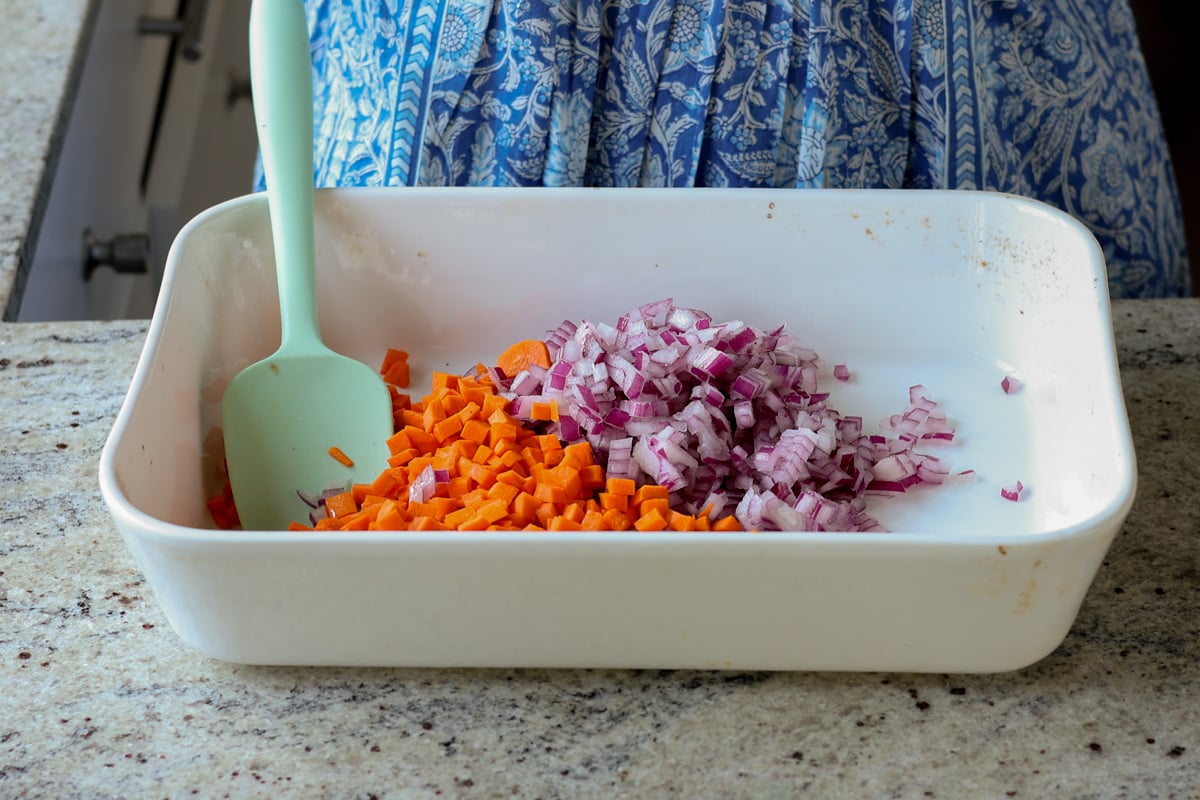 adding carrots and onion to the baking pan