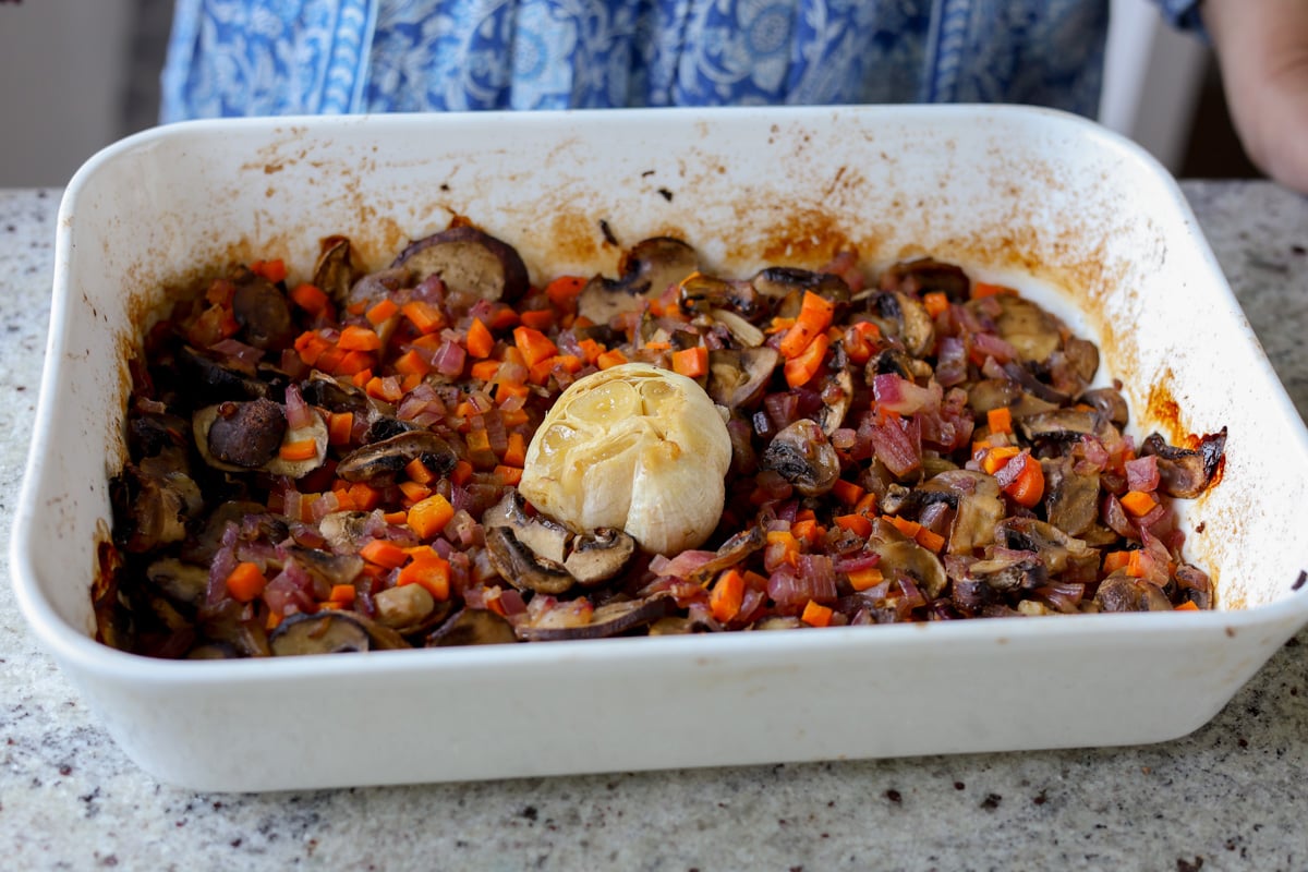 roasted veggies and garlic head in the baking pan