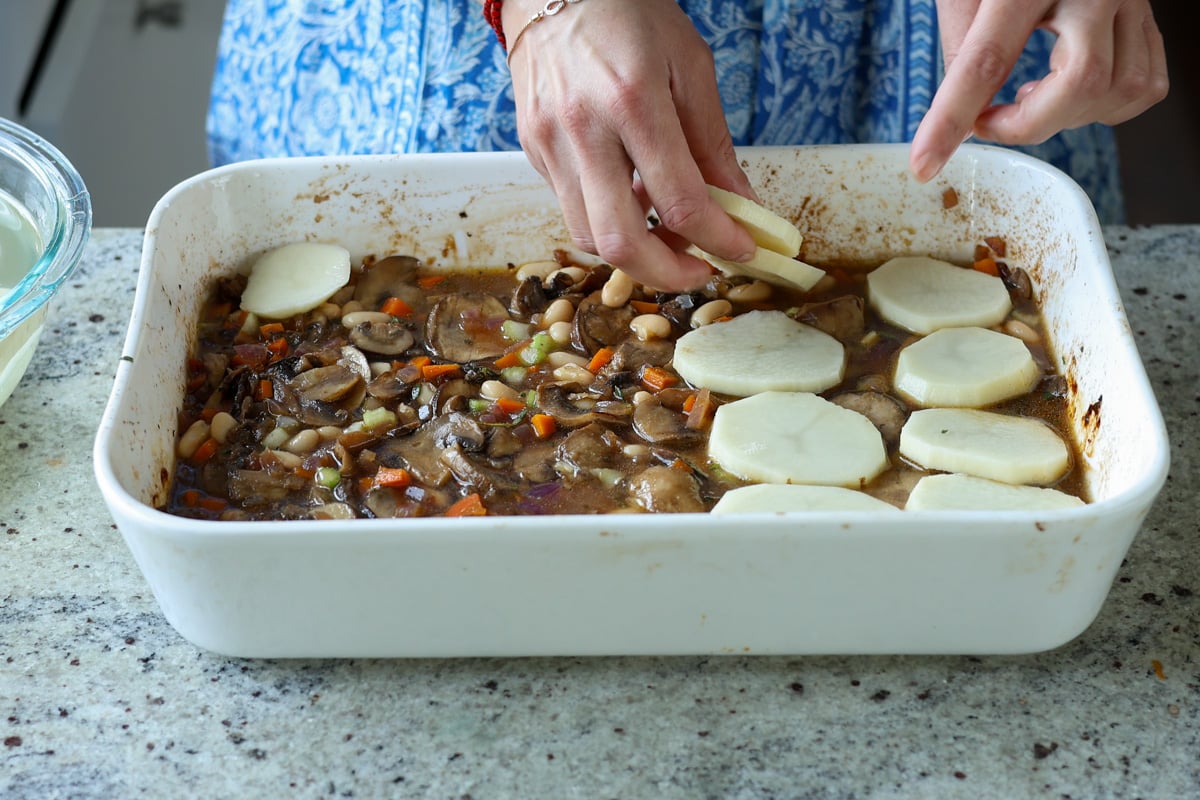layering the potatoes on top of the bean-veggie mixture