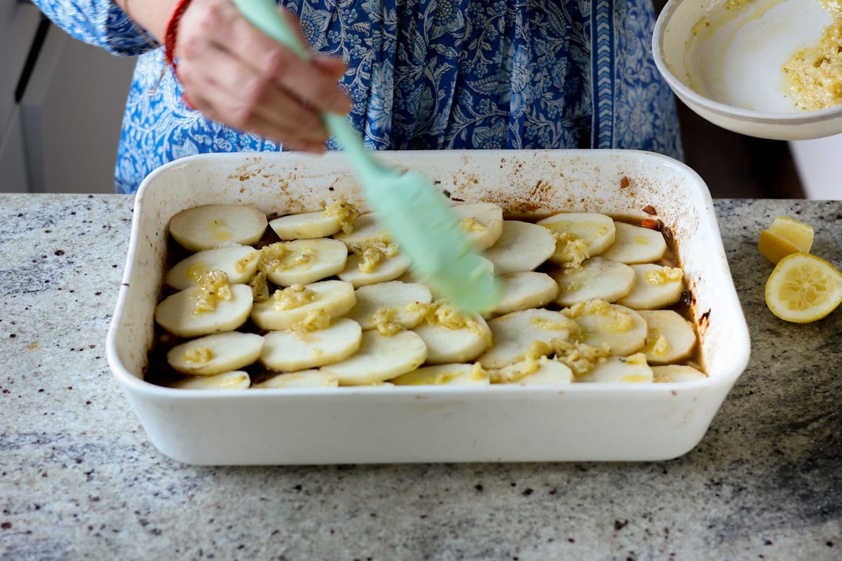 spreading the garlic butter onto the potatoes