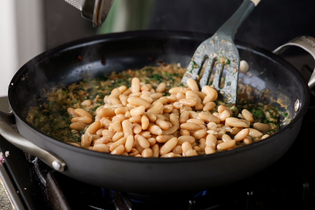 adding white beans to the pan