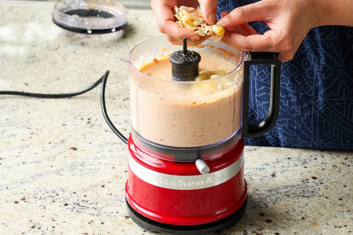 adding roasted garlic to the food processor