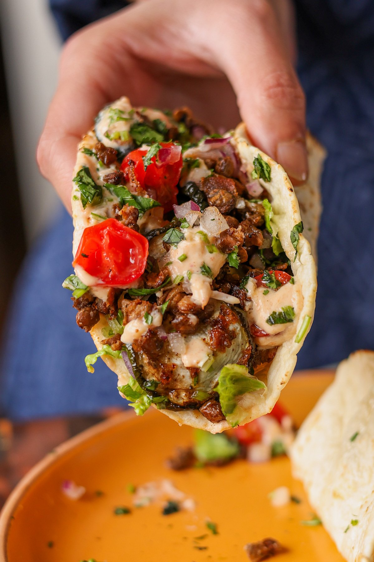 hand holding a taco made from the whipped tofu, zucchini, and lentils