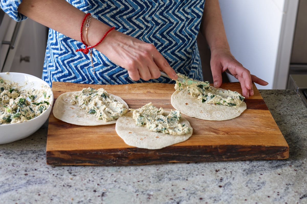 spreading the tofu ricotta onto the tortillas