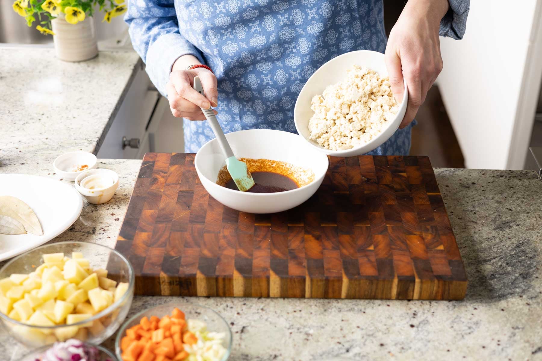 adding crumbled tofu to the bowl of marinade