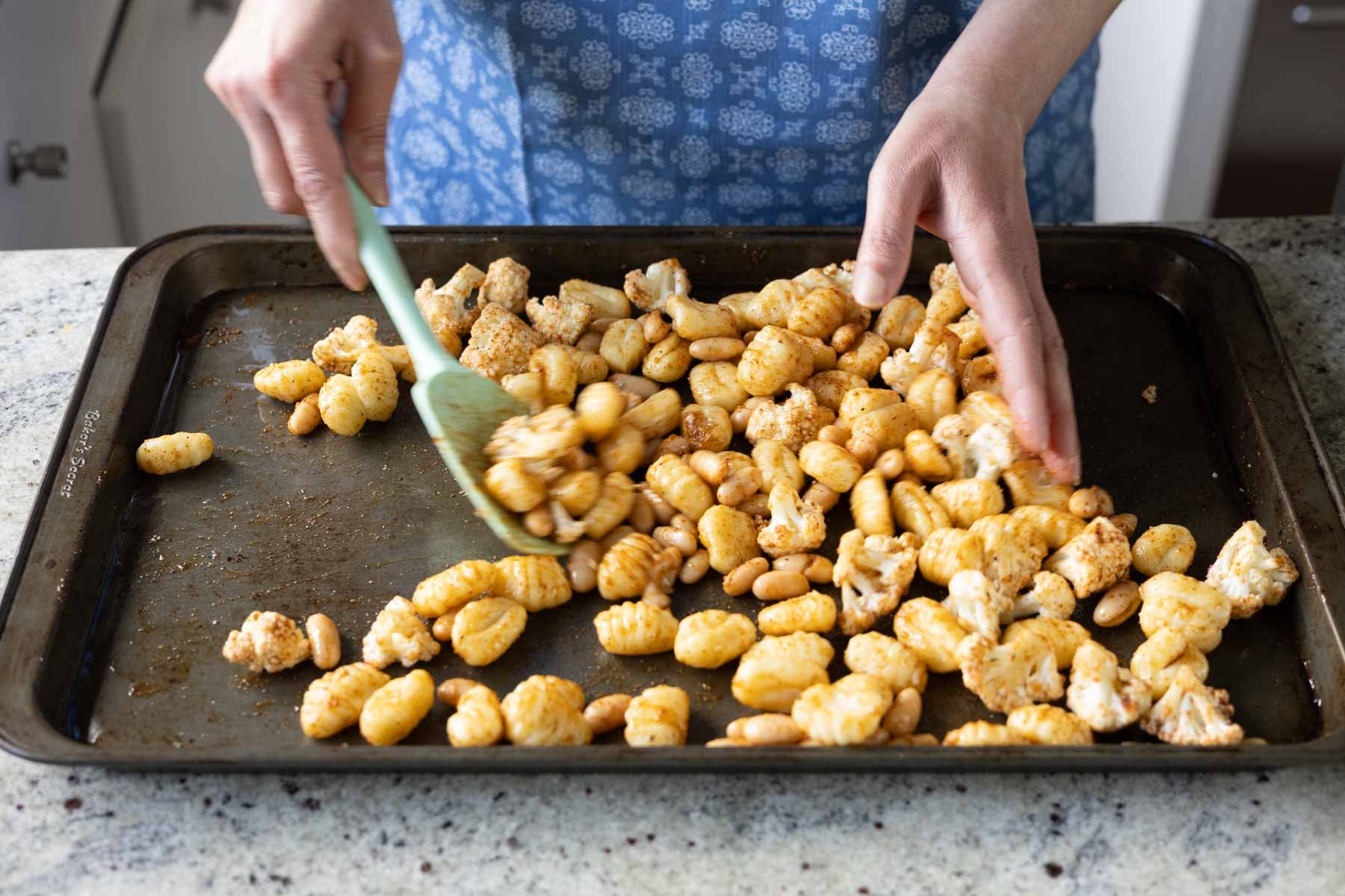 tossing the gnocchi, beans, and veggies with the spices and oil
