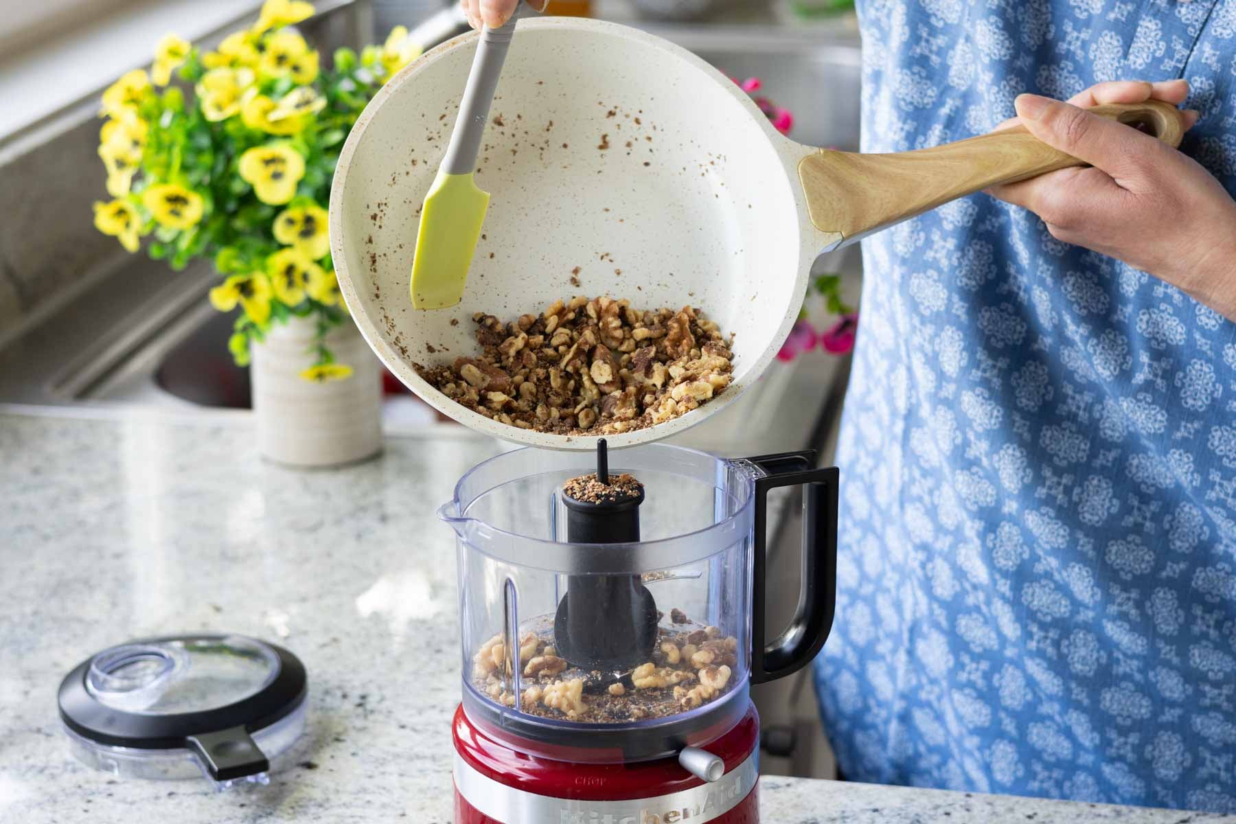 adding toasted walnuts to the food processor