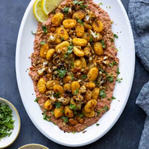 crispy gnocchi muhammara on a plate with lemon slices