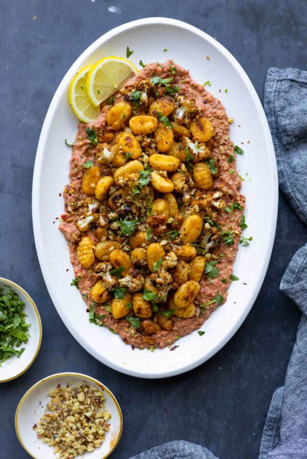 crispy gnocchi muhammara on a plate with lemon slices