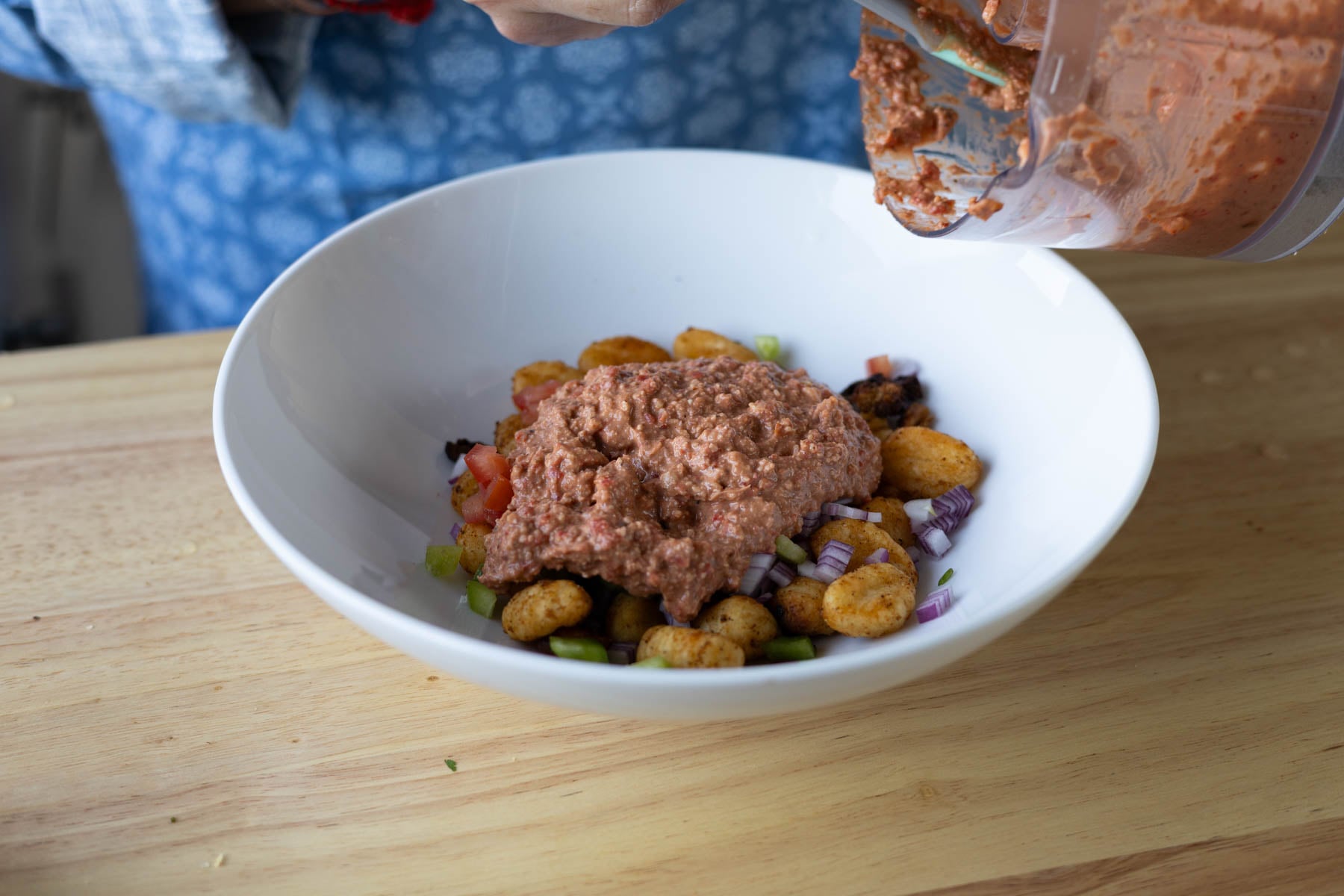 adding the gnocchi mixture, veggies, and bean dip to a bowl