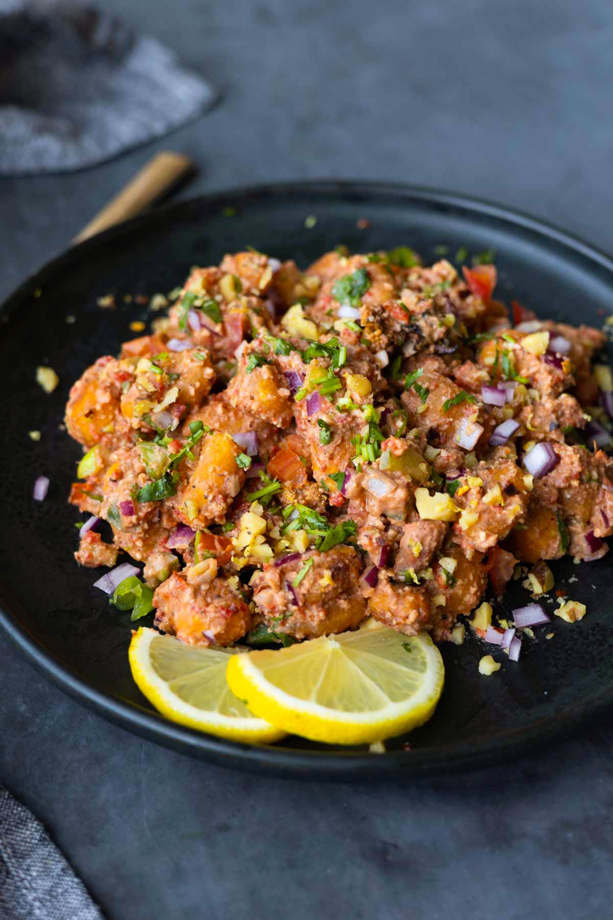 crispy gnocchi muhammara salad on a plate with lemon slices
