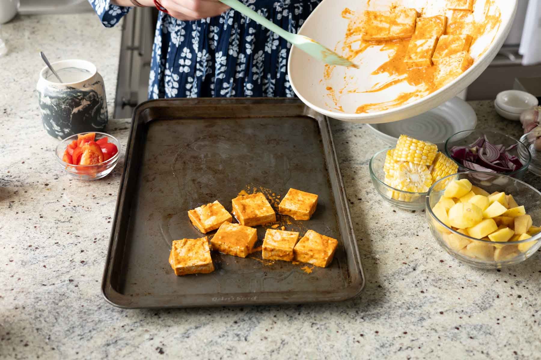 spreading the peri-peri tofu onto half of a greased baking sheet