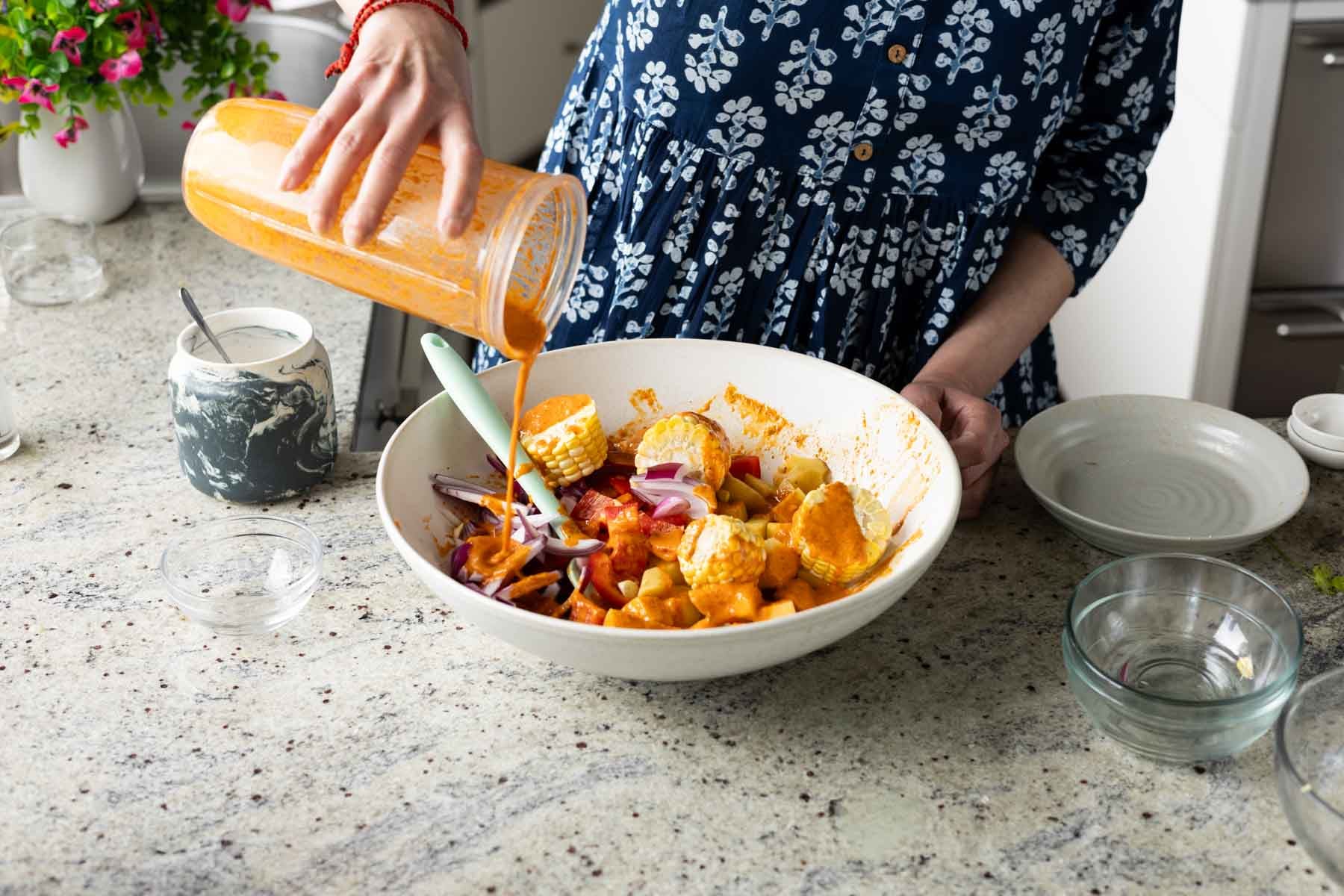 pouring peri-peri marinade onto the veggies