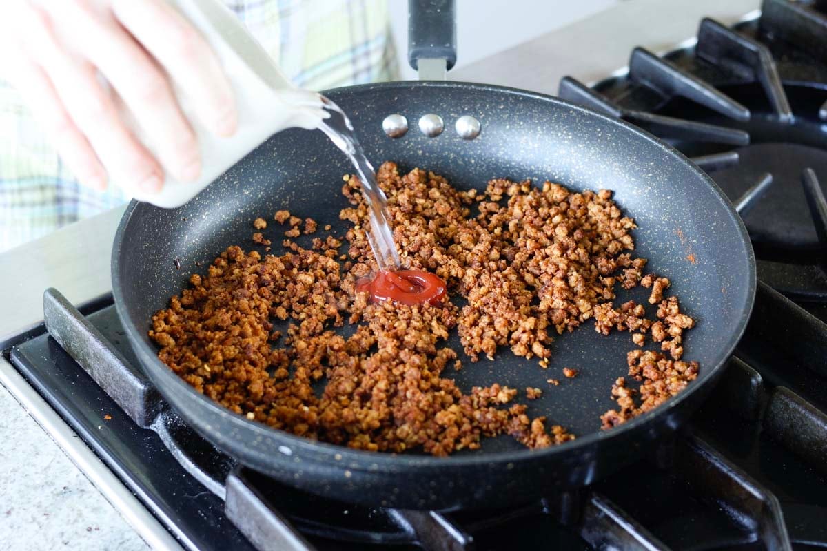 adding ketchup and water to the pan