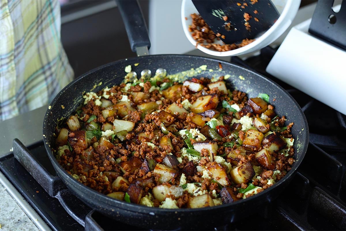 adding potato mixture and more sausage to skillet