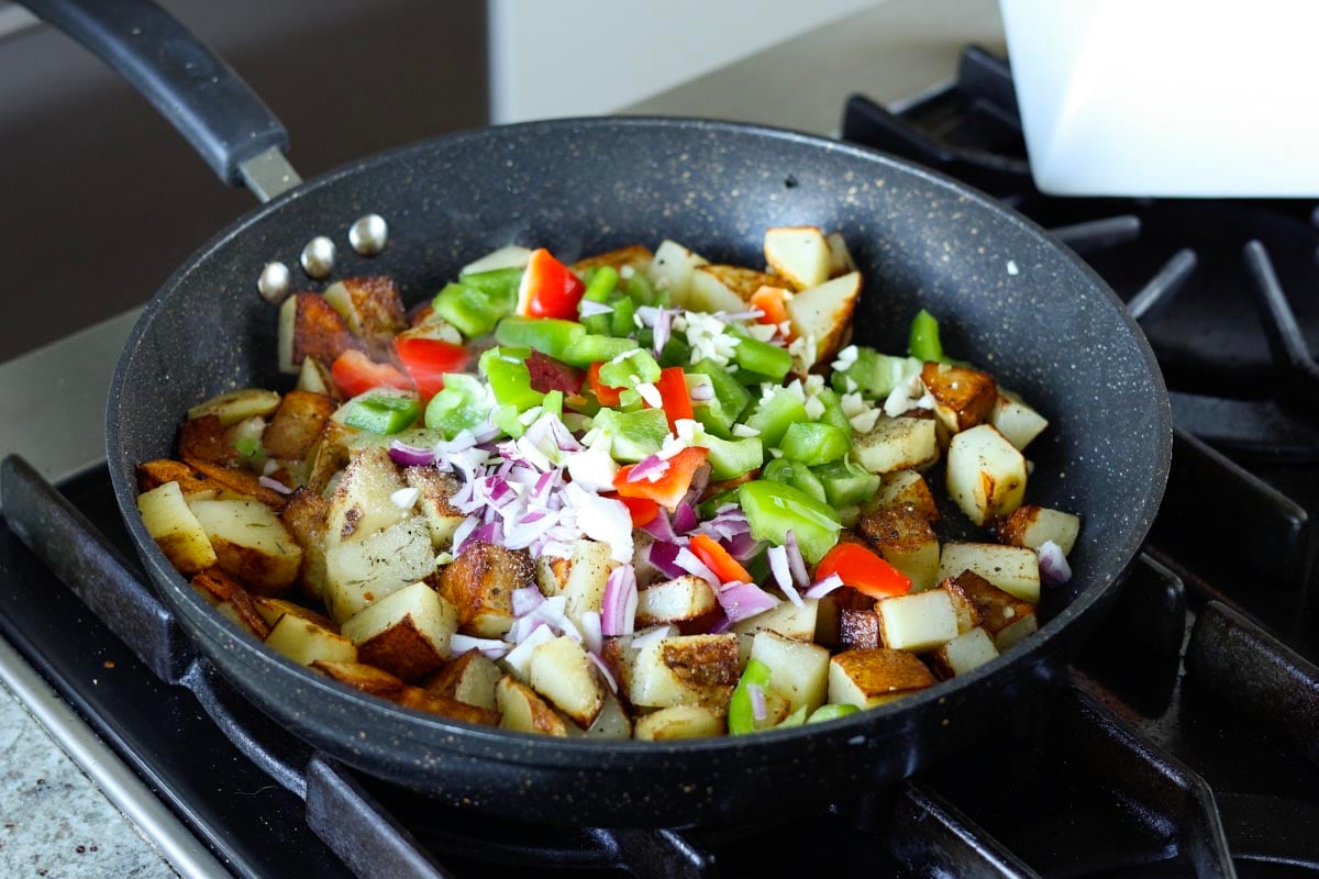 adding veggies and herbs to the potatoes