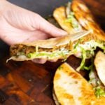 hand holding a paratha tacos after stuffing with raita and greens