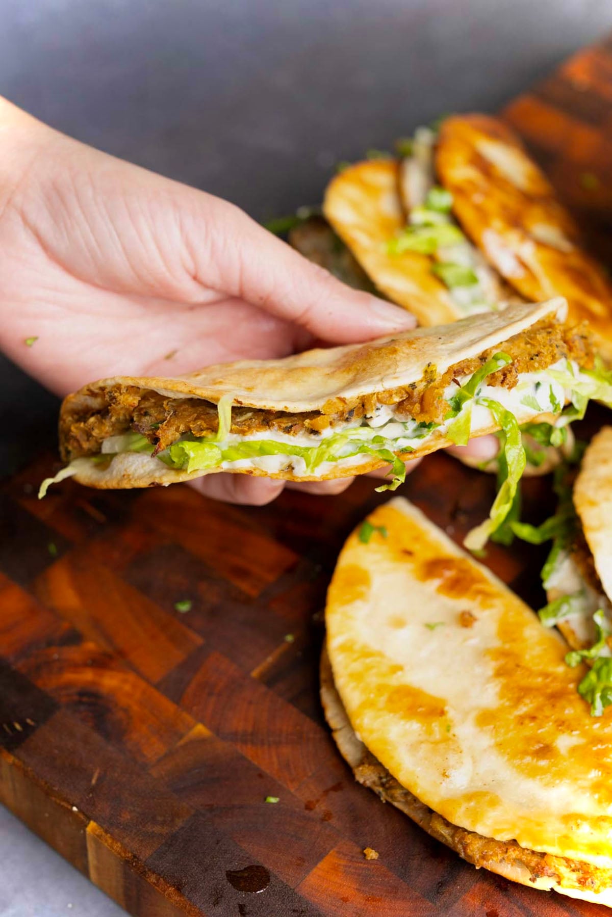 hand holding a paratha tacos after stuffing with raita and greens