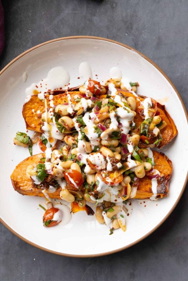 marinated white bean salad over sweet potatoes with creamy sauce on top