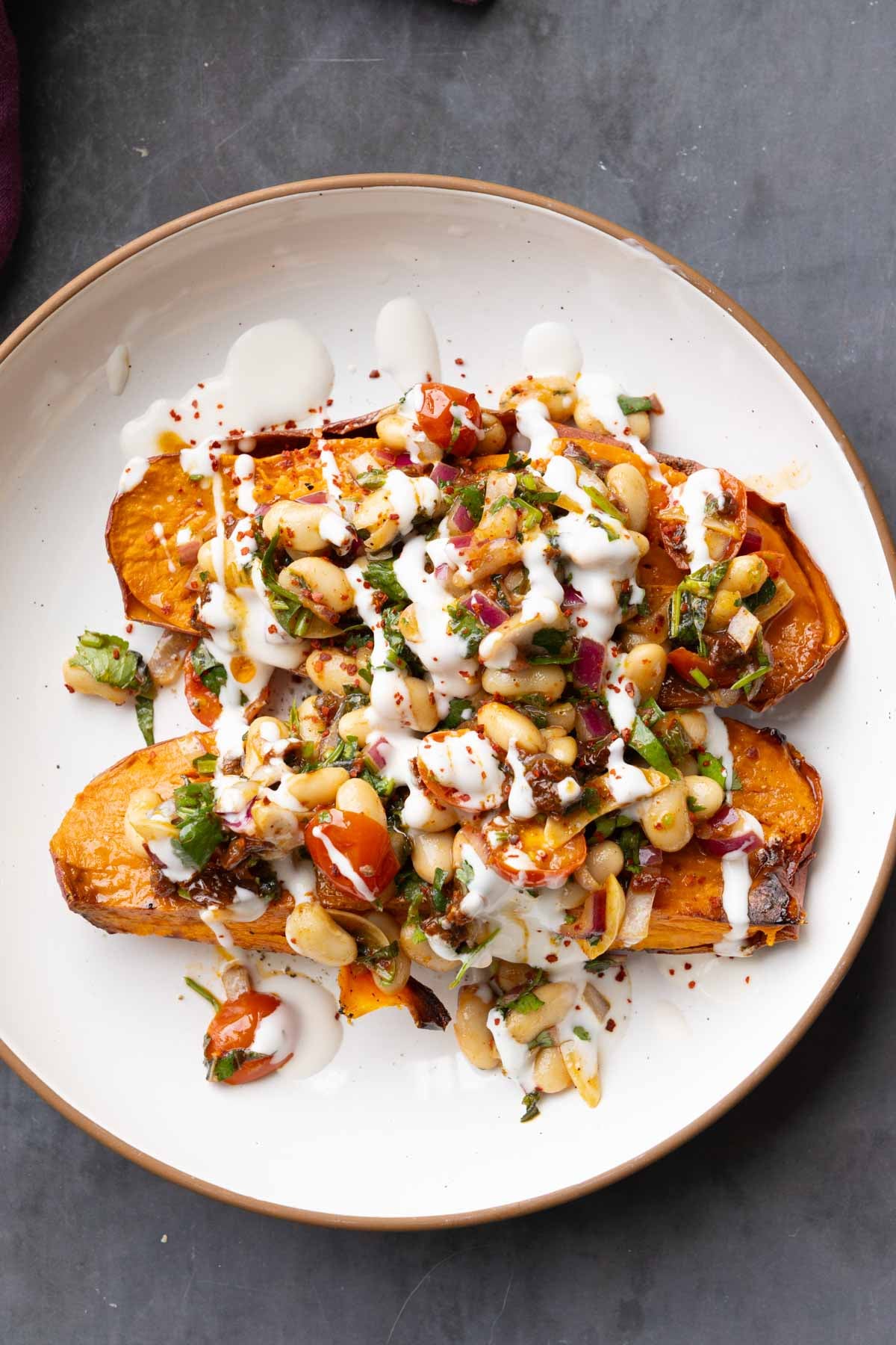 marinated white bean salad over sweet potatoes with creamy sauce on top