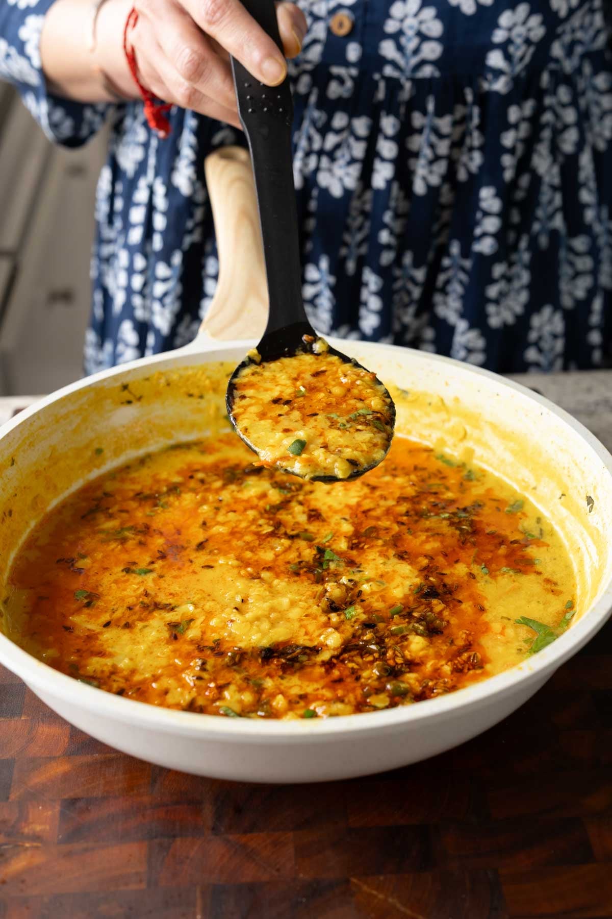 spoon serving jeera dal from the pan