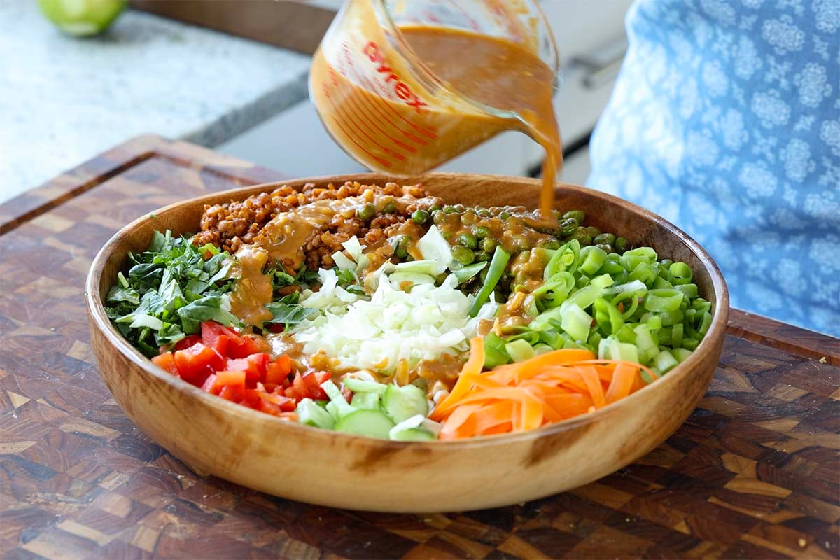 adding the dressing to the gochujang salad